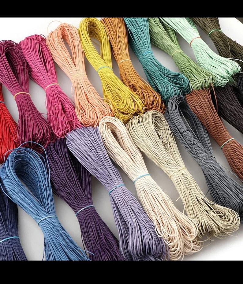 May include: Assortment of colorful waxed cotton cords, perfect for crafting and jewelry making. The cords are arranged in a rainbow pattern, with colors including red, orange, yellow, green, blue, purple, brown, and white.