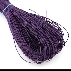 May include: A spool of deep purple waxed cotton cord. The cord is tightly wound and ready for crafting projects.