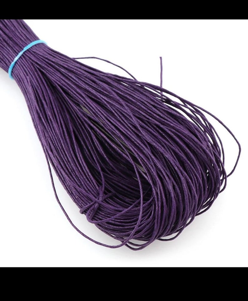 May include: A spool of deep purple waxed cotton cord. The cord is tightly wound and ready for crafting projects.
