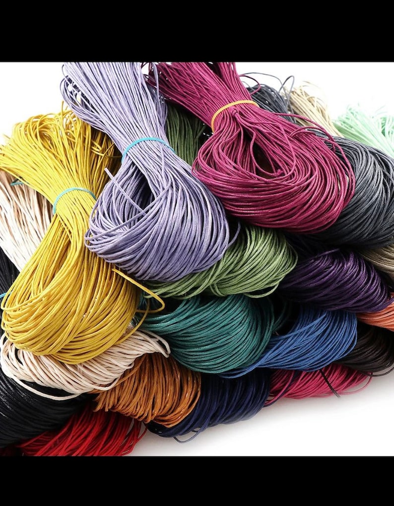 May include: A variety of colors of waxed cotton cord, including black, white, red, yellow, green, blue, purple, and brown. The cords are bundled together and are ready to be used for crafting projects.
