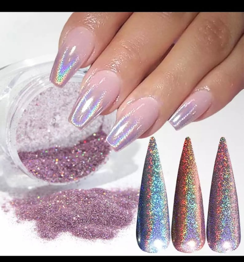 May include: A jar of iridescent glitter with a pink hue. The glitter is shown on a fingernail with a holographic finish.