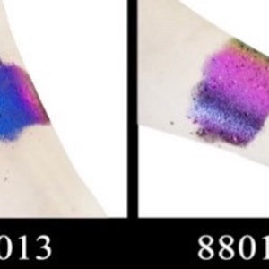 Op de afbeelding: Twee swatches van iriserende glitter op de arm van een persoon. De swatch links is blauw en paars. De swatch rechts is roze en paars. De swatches zijn gelabeld 88013 en 88014.