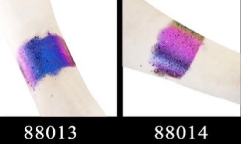 Op de afbeelding: Twee swatches van iriserende glitter op de arm van een persoon. De swatch links is blauw en paars. De swatch rechts is roze en paars. De swatches zijn gelabeld 88013 en 88014.
