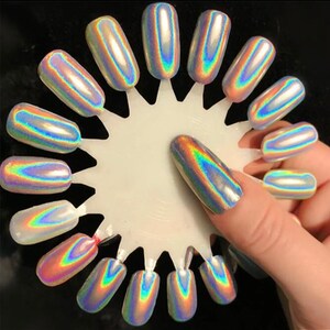 May include: A white circular display with 15 iridescent nail polish colors. The colors are arranged in a circle with a fingernail painted with one of the colors.