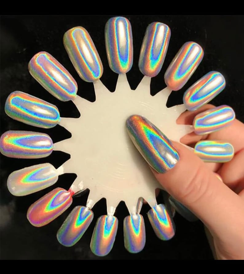 May include: A white circular display with 15 iridescent nail polish colors. The colors are arranged in a circle with a fingernail painted with one of the colors.
