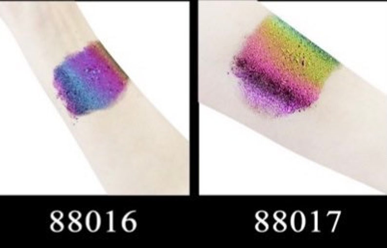 Op de afbeelding: Twee swatches van iriserende glitter oogschaduw op de arm van een persoon. De swatch aan de linkerkant is een blauwe en paarse glitter met een roze tint. De swatch aan de rechterkant is een groene en roze glitter met een paarse tint. De swatches zijn gemarkeerd met 88016 en 88017.