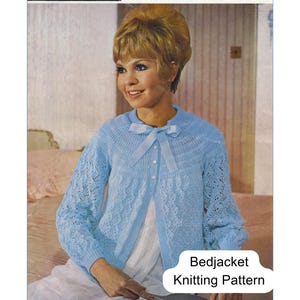 Puede incluir: Un patrón de tejido vintage Wendy para una chaqueta de cama azul claro, modelo 855. El patrón muestra un cárdigan de punto azul claro con cuello redondo, cierre de lazo y detalles de punto calado en las mangas y el cuerpo de la prenda.