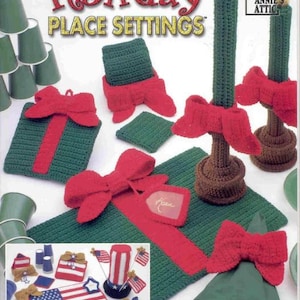 Puede incluir: Un libro de patrones de ganchillo titulado "Holiday Place Settings" con varios artículos de ganchillo. La imagen muestra manteles individuales verdes, lazos rojos y candelabros. También hay artículos de ganchillo más pequeños con un tema de la bandera estadounidense.