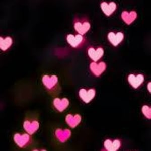 May include: A dark background with a scattering of pink heart-shaped bokeh lights.