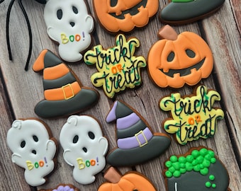 May include: A collection of Halloween-themed sugar cookies decorated with various designs, including ghosts, pumpkins, witches' hats, cauldrons, and the phrase "trick or treat".