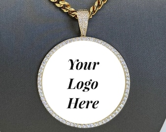 May include: A gold chain necklace with a round pendant featuring a white background and the text "Your Logo Here" in black. The pendant is surrounded by a row of clear stones.