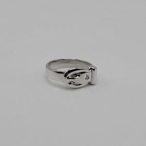 May include: A polished silver-toned ring featuring a design that mimics a belt, complete with a buckle-shaped focal point on the front. The band is smooth and uniform, showcasing a reflective metallic finish throughout the entire piece.