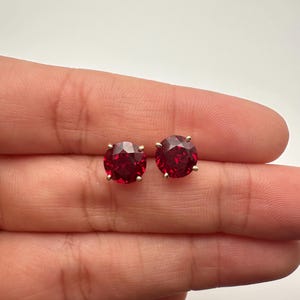 May include: A pair of gold stud earrings with round red gemstones.