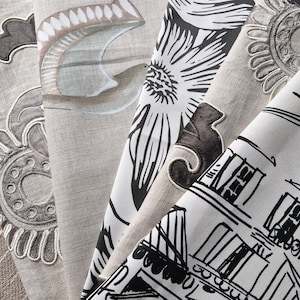 May include: Close-up of fabric swatches featuring diverse patterns. Designs include floral, architectural, and abstract motifs in neutral tones with black and grey accents. The fabrics appear to be linen or a similar textured material.