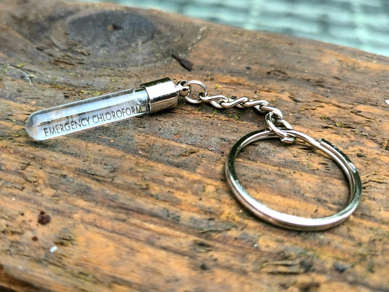 May include: A silver keychain with a clear glass vial that says "EMERGENCY CHLOROFORM" on it.