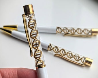 Könnte beinhalten: Ein weißer Stift mit einer goldenen Kappe und einem durchsichtigen Schaft, gefüllt mit einem goldfarbenen DNA-Helix-Design.