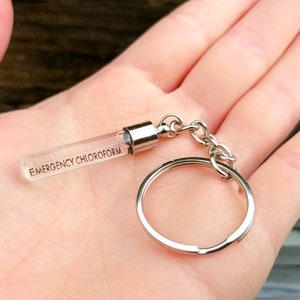 May include: A silver keychain with a clear glass vial that says "EMERGENCY CHLOROFORM" on it.