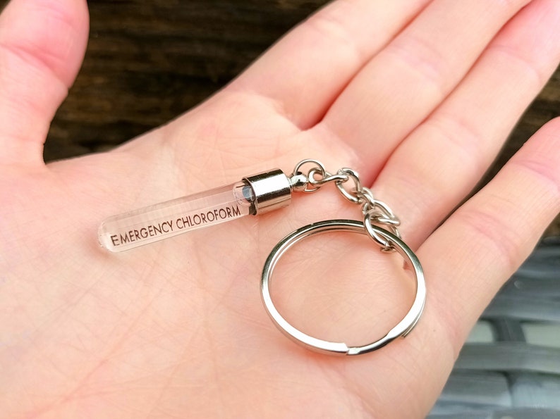 May include: A silver keychain with a clear glass vial that says "EMERGENCY CHLOROFORM" on it.