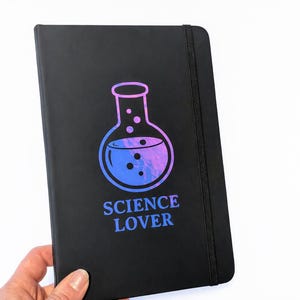 Op de afbeelding: Een witte keramische mok met een zwart handvat en de tekst "But First, Coffee" in een handschriftstijl. De mok staat op een wit oppervlak. De mok is ongeveer 10 cm hoog.