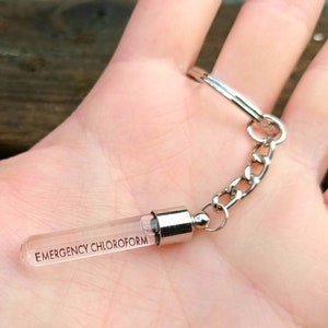 May include: A silver keychain with a clear glass vial that says "EMERGENCY CHLOROFORM" on it.