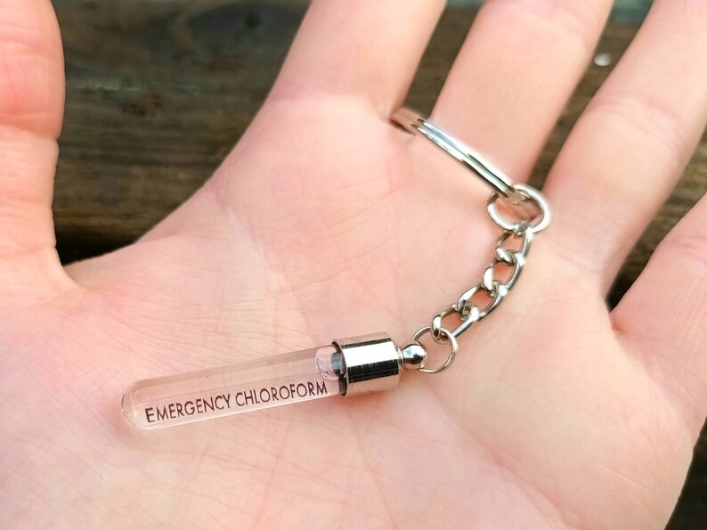 May include: A silver keychain with a clear glass vial that says "EMERGENCY CHLOROFORM" on it.