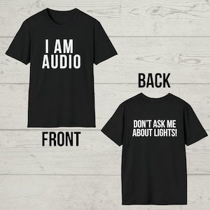 Op de afbeelding: Zwart T-shirt met witte tekst aan de voorkant die "I AM AUDIO" zegt en witte tekst aan de achterkant die "DON'T ASK ME ABOUT LIGHTS!" zegt.