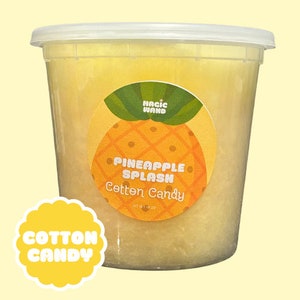 May include: A clear plastic container filled with yellow cotton candy. The container has a label with a pineapple graphic and the text "Pineapple Splash Cotton Candy".