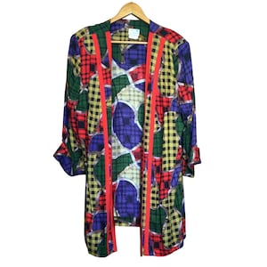 May include: A long-sleeved, open-front jacket with a vibrant pattern of plaid and geometric shapes in red, green, yellow, and blue. The jacket features vertical red stripes and is hanging on a wooden hanger.