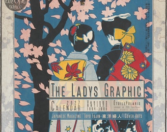 May include: A 2027 wall calendar titled The Ladys Graphic featuring Japanese magazine cover art. The illustration shows two figures in traditional attire standing under a cherry blossom tree with pink petals against a blue background.
