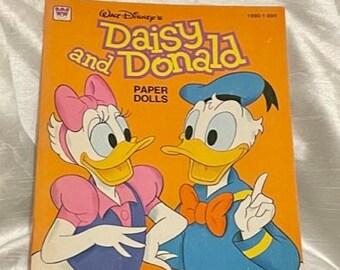 May include: A vintage Walt Disney's Daisy and Donald paper doll book with a yellow cover featuring illustrations of Daisy Duck and Donald Duck. The book title is "Daisy and Donald Paper Dolls" and the copyright date is 1980-1-828.