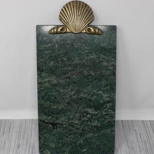 May include: A green marble serving tray with a brass seashell design. The tray is rectangular and has a smooth surface.