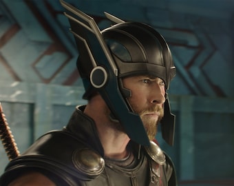 May include: A man wearing a black and blue helmet with a silver trim and a black and silver armor. He has a beard and is looking to the right.