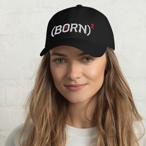 May include: A black baseball cap with white embroidered text that reads "(BORN)2".