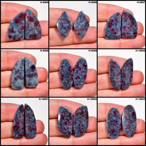 May include: Nine pairs of polished gemstones with a blue-gray matrix and red inclusions. The gemstones vary in shape, including teardrop, diamond, and oval. Each pair is displayed on a hand.