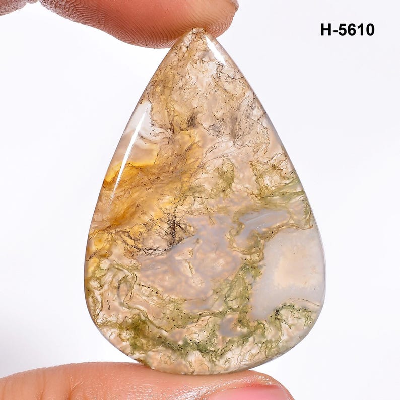 May include: A teardrop-shaped moss agate gemstone with a polished surface. The stone features a mix of translucent white, beige, and green hues, with intricate patterns resembling moss or foliage. The text "H-5610" is visible in the upper right corner.