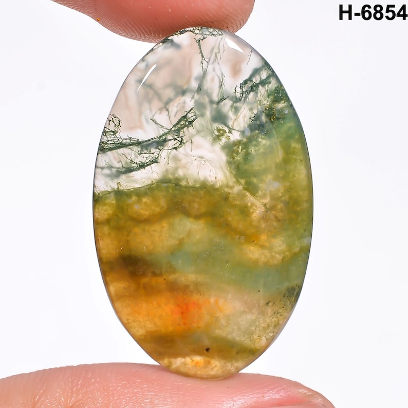 May include: An oval-shaped moss agate gemstone with a mix of colors. The stone features a translucent white base with green, yellow, and orange inclusions. The text "H-6854" is visible in the upper right corner.