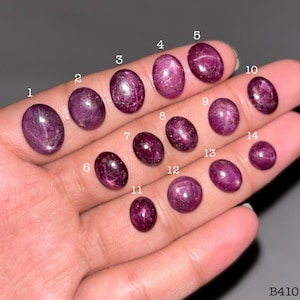 Puede incluir: Una colección de catorce rubíes estrella de color magenta intenso, de forma ovalada y pulidos en cabujones lisos. Las piedras preciosas están numeradas del uno al catorce y muestran un efecto de estrella de seis rayos, etiquetadas B410.