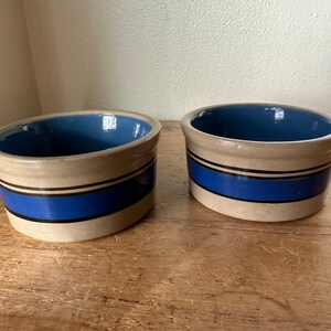 May include: Two stoneware bowls with blue and black stripes. The bowls are glazed inside and have a rustic, handmade look.