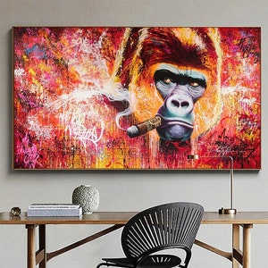 May include: A vibrant painting of a gorilla smoking a cigar. The artwork features a colorful background with graffiti-style elements. The gorilla's face is detailed with a serious expression, and the cigar is lit. The painting is framed and displayed above a wooden desk.