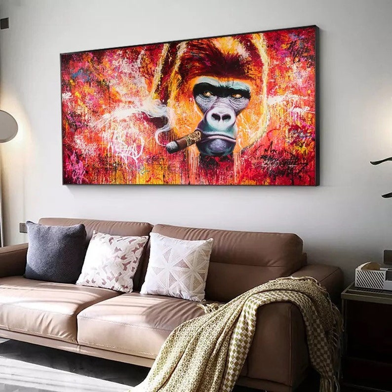 K&ouml;nnte beinhalten: Ein gro&szlig;es, gerahmtes Leinwandbild mit einem Gorilla, der eine Zigarre raucht. Das Kunstwerk verwendet eine lebendige Farbpalette aus Rot, Orange und Gelb mit Graffiti-Akzenten. Das Gesicht des Gorillas ist detailliert mit einem ernsten Ausdruck.