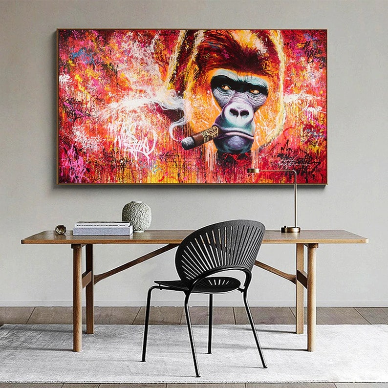 K&ouml;nnte beinhalten: Ein gro&szlig;es, gerahmtes Leinwandbild, das einen Gorilla mit Zigarre im Graffiti-Stil zeigt. Das Kunstwerk hat einen roten, orangefarbenen und gelben Hintergrund mit detailliertem Gorillagesicht. Der Gesamtstil ist urban.