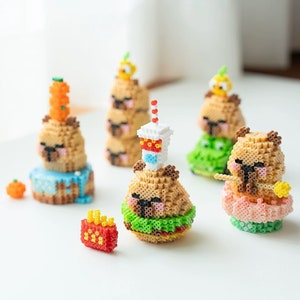 May include: Five small, colorful, beaded figurines of cartoon animals wearing different outfits. The figurines are made of colorful plastic beads and are arranged on a white surface.