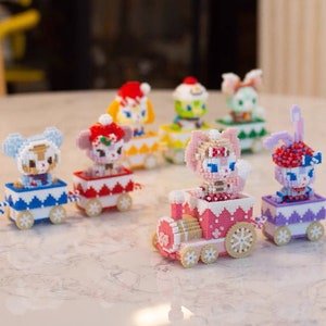 Puede incluir: Un conjunto de siete vagones de tren de cuentas de colores con personajes de animales de dibujos animados. Cada vagón tiene un animal diferente, incluyendo un oso, un gato, un conejo y un pájaro. Los vagones de tren están decorados con copos de nieve y otros detalles de temática invernal.