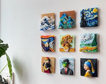 May include: A white wall with nine framed pixel art pieces depicting famous paintings. The paintings include The Great Wave off Kanagawa, Starry Night, The Scream, Sunflowers, Girl with a Pearl Earring, and more.