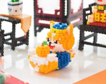 May include: A set of miniature furniture and figurines made of colourful beads. The set includes two black chairs, a table with a potted plant, a screen, and two orange and yellow figurines wearing traditional Chinese clothing.