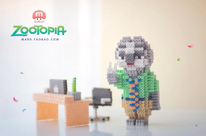 May include: A gray and white bead figurine of a character from the movie Zootopia, wearing a green shirt and a tie. The figurine is standing on a white surface with a desk and chair in the background. The text "Zootopia" and "MARD.TAOBAO.COM" is visible in the top left corner of the image.