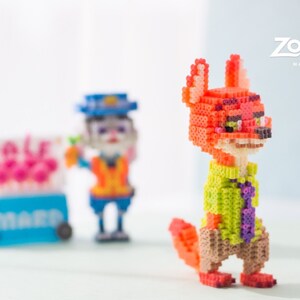 May include: A red fox character with a green shirt and purple tie, made of colorful plastic beads. The character is from the animated movie Zootopia.