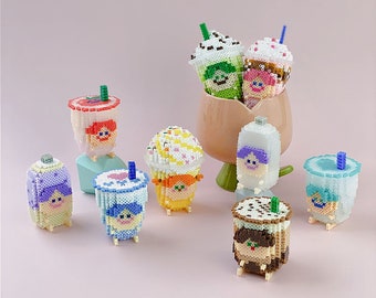 May include: A collection of colorful, pixelated drink sculptures, including bubble tea and iced coffee designs. The sculptures feature various colors and patterns, with details like straws and whipped cream. They are arranged on a pink background.