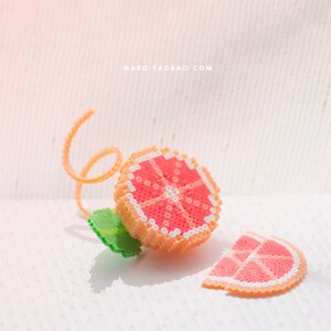 May include: A pink and white beaded grapefruit with a green leaf and a curled orange beaded stem. A slice of grapefruit is also shown.