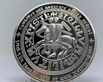 Könnte beinhalten: Eine silberne Münze mit einem Ritter zu Pferd und der Inschrift "SIGILLVM MILITVM XPISTI" am Rand. Die Münze hat ein detailliertes Design und ist vor einem weißen Hintergrund platziert.